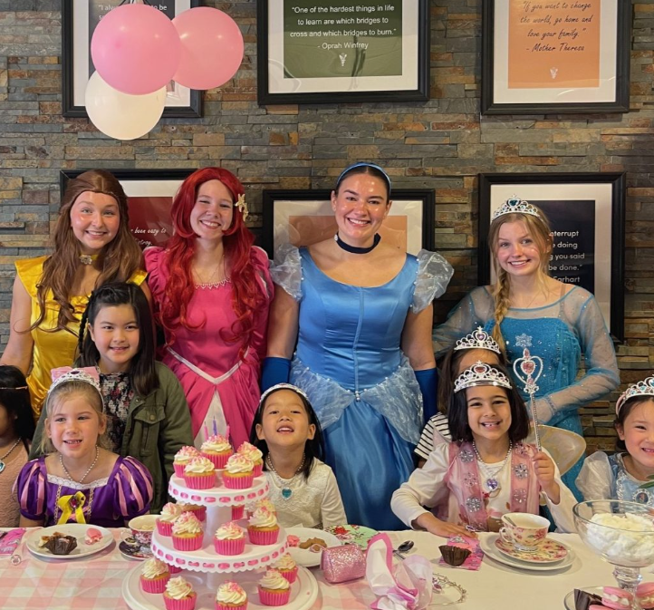 a group of people posing for a photo in front of a birthday cake