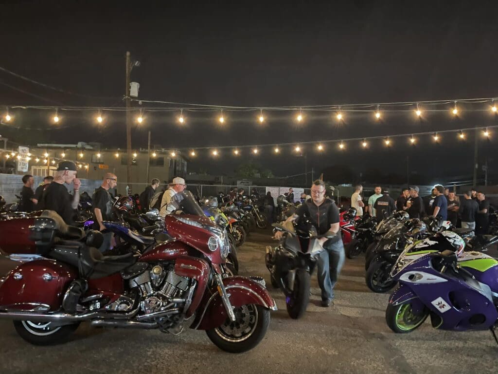 a group of people standing around a motorcycle in a parking lot